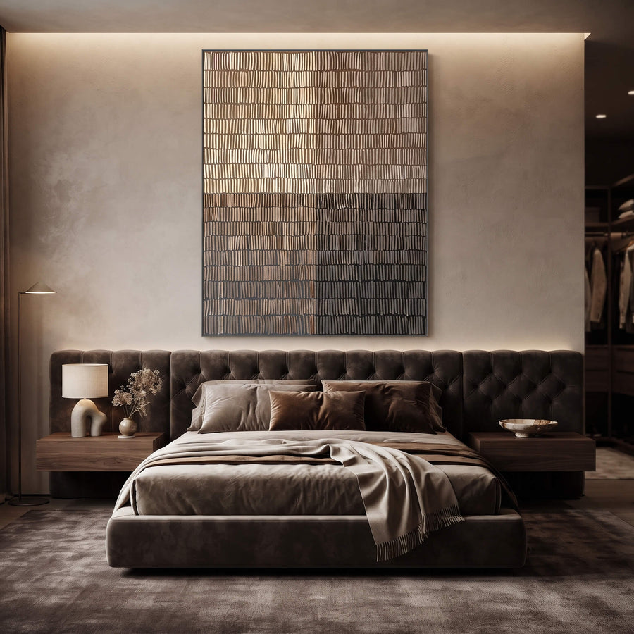 A modern bedroom featuring a low tufted platform bed in dark brown velvet, styled with matching brown bedding and pillows. The bed is centered beneath a large vertical abstract canvas art piece on a textured beige wall, flanked by matching wood nightstands with a lamp and decorative vase.