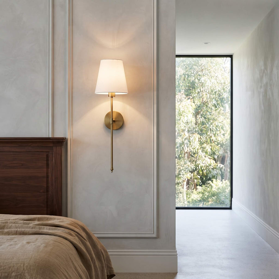 Brass finish stem and tapered shade on a panelled bedroom wall