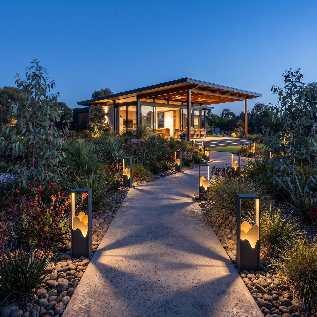 Ridge path lights illuminating a landscaped garden bed at dusk