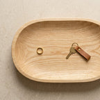 Wooden tray with a gold ring and keys on a beige background