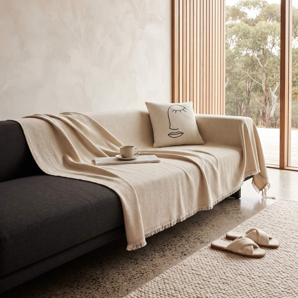 Beige sofa cover throw draped over a dark upholstered sofa