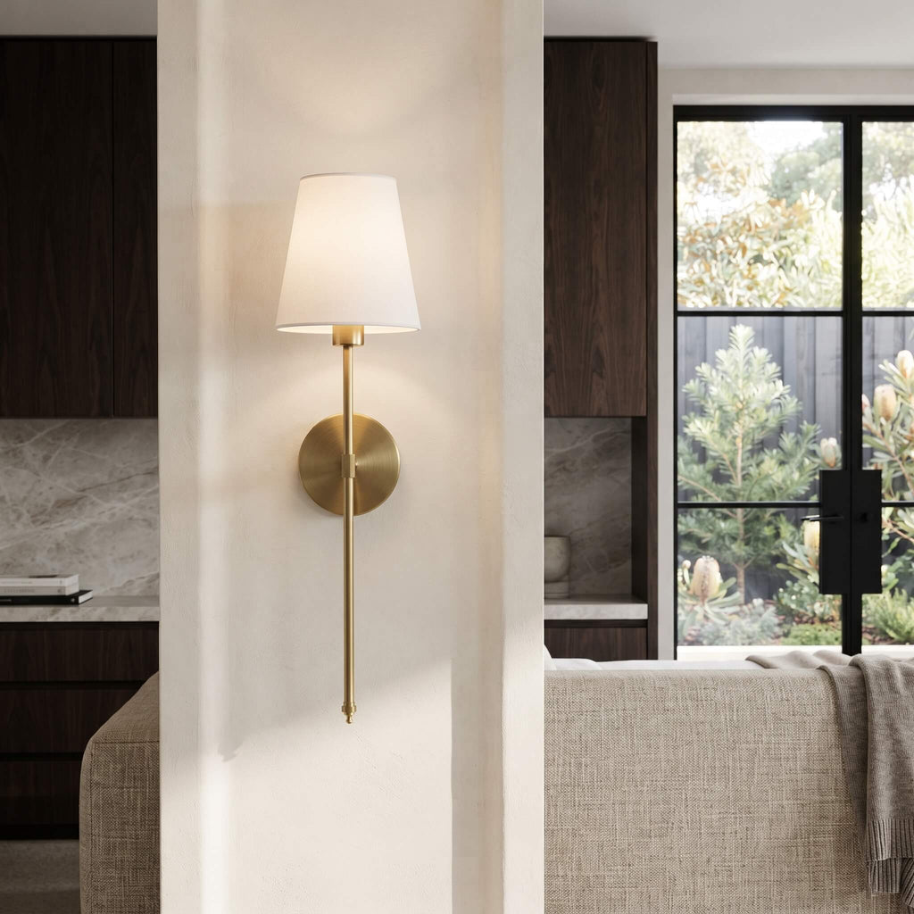 Brass wall sconce on a wall between a kitchen and living area