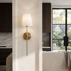 Brass wall sconce on a wall between a kitchen and living area