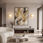 Brass globe wall sconces flanking artwork in a living room