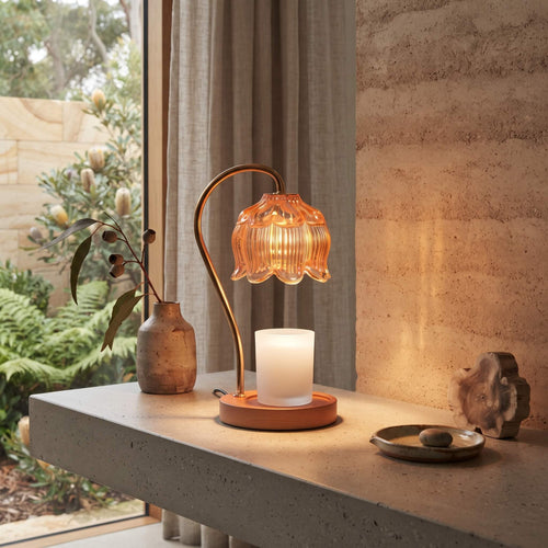 Amber glass candle warmer lamp lit on a console table