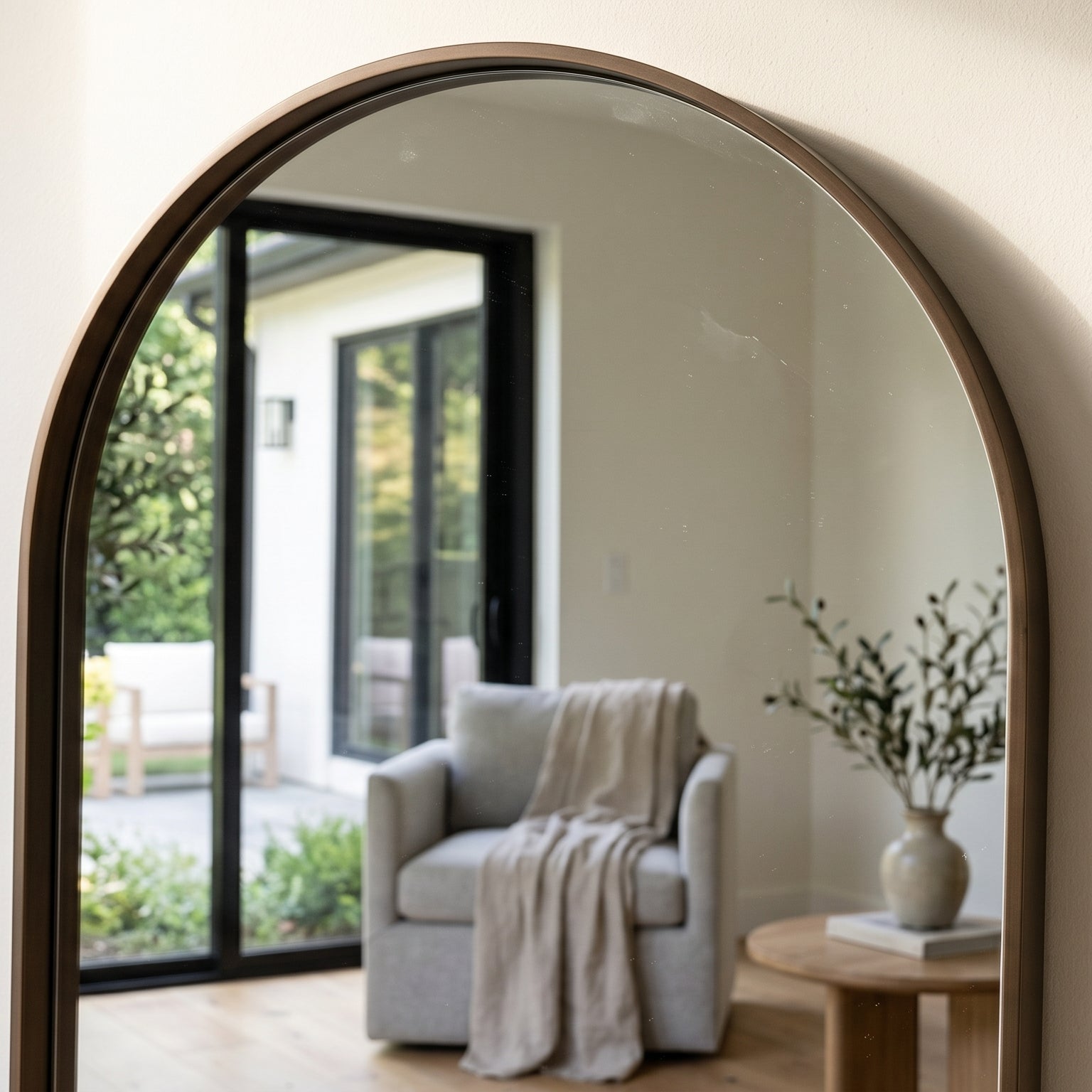 Large round mirror on a wall reflecting a living room with a sofa and plants.