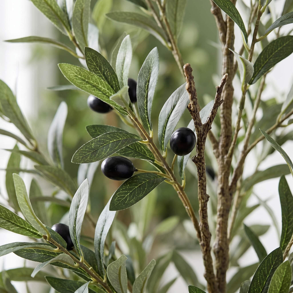 Artificial olive branch with green leaves and glossy black olives on a white background.