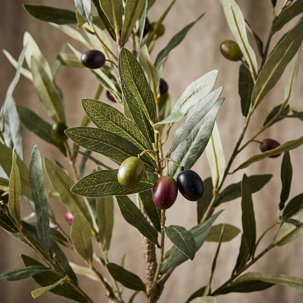 An artificial olive branch with realistic green and black olives, detailed leaves, and a textured brown trunk against a soft beige background.