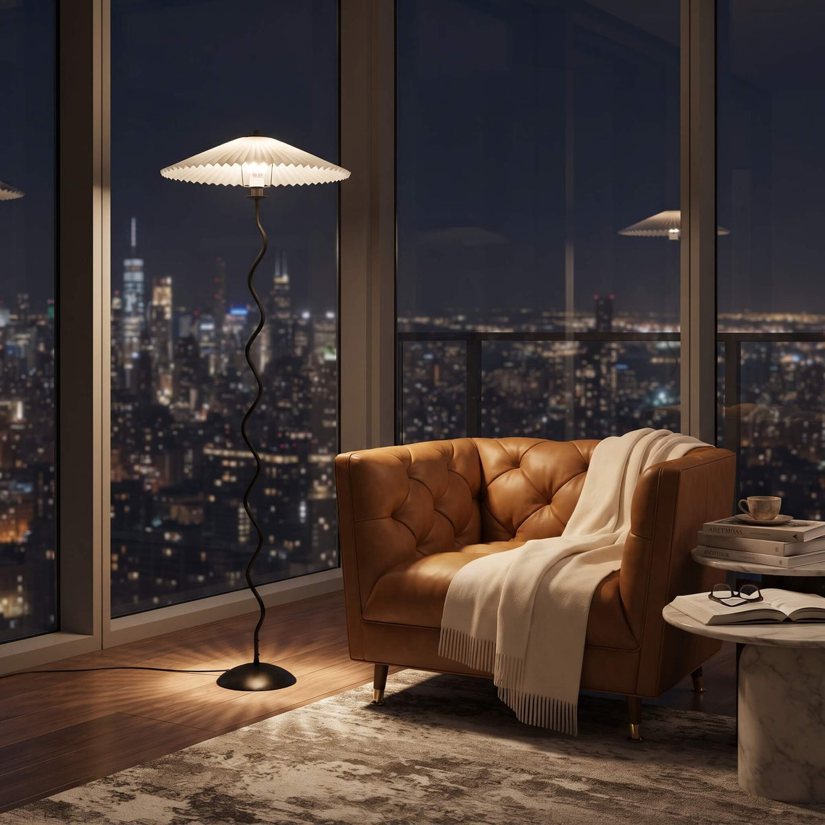 A modern black spiral floor lamp with a white pleated drum shade stands beside a brown leather armchair in a city-view room at night, with a cream throw blanket draped over the chair.