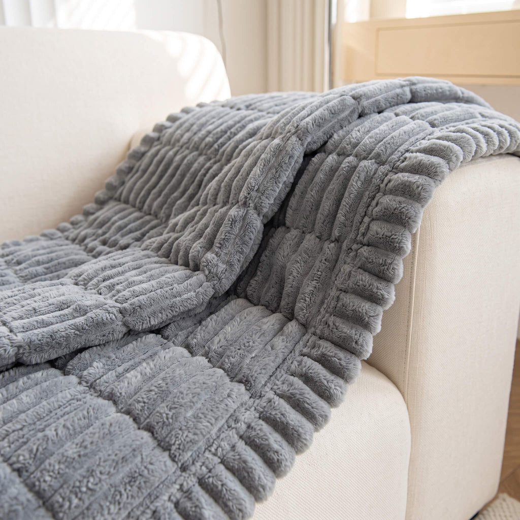 Grey quilted sofa cover draped over a curved sofa arm