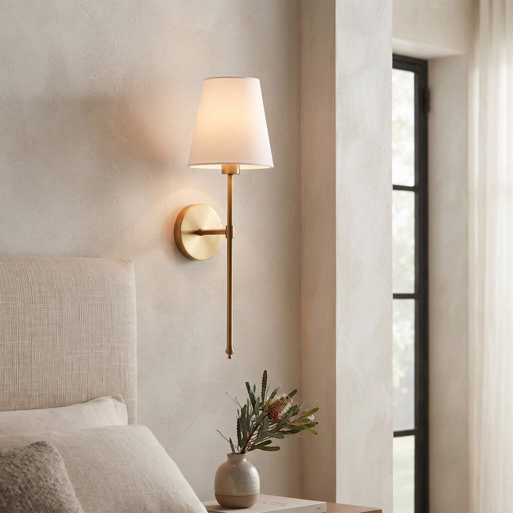 Brass wall sconce beside an upholstered bedhead with native flowers