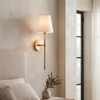 Brass wall sconce beside an upholstered bedhead with native flowers