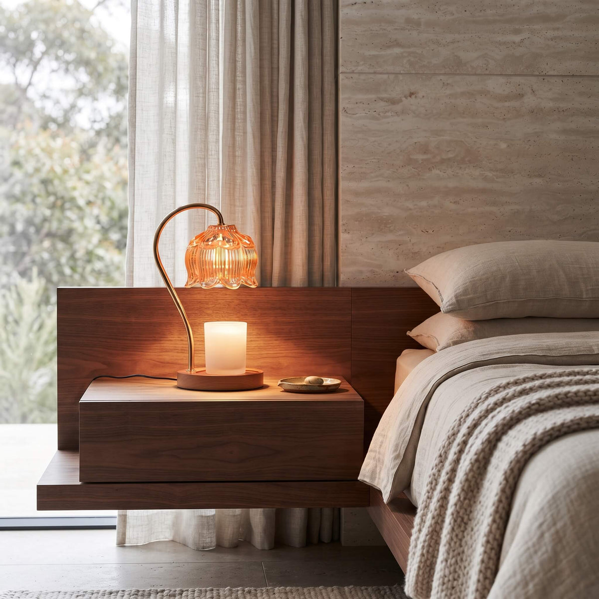Amber glass candle warmer lamp on a bedside table