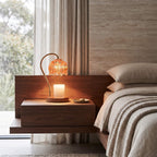 Amber glass candle warmer lamp on a bedside table