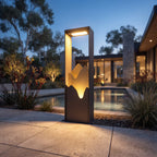 Ridge bollard light glowing warm beside a modern home at dusk