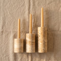 Three candles in wooden candle holders on a textured beige background