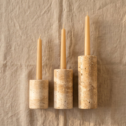 Three candles in wooden candle holders on a textured beige background
