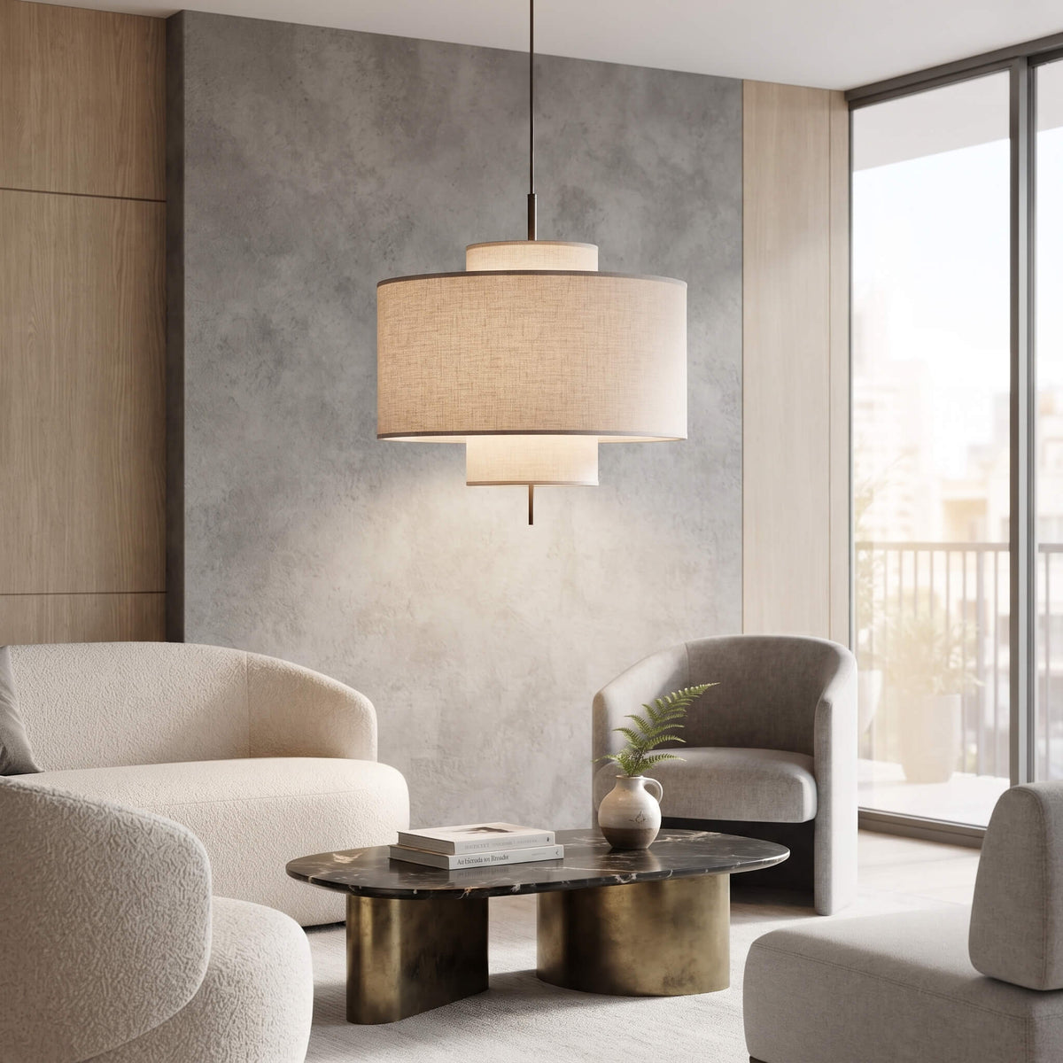 A modern two-tier drum pendant light with a beige linen-textured shade hangs in a contemporary living room with neutral-toned armchairs and a marble coffee table.