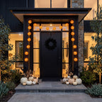Pumpkin lantern lights framing a dark front door with white pumpkins