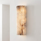 Fluted alabaster wall sconce lit against a white wall