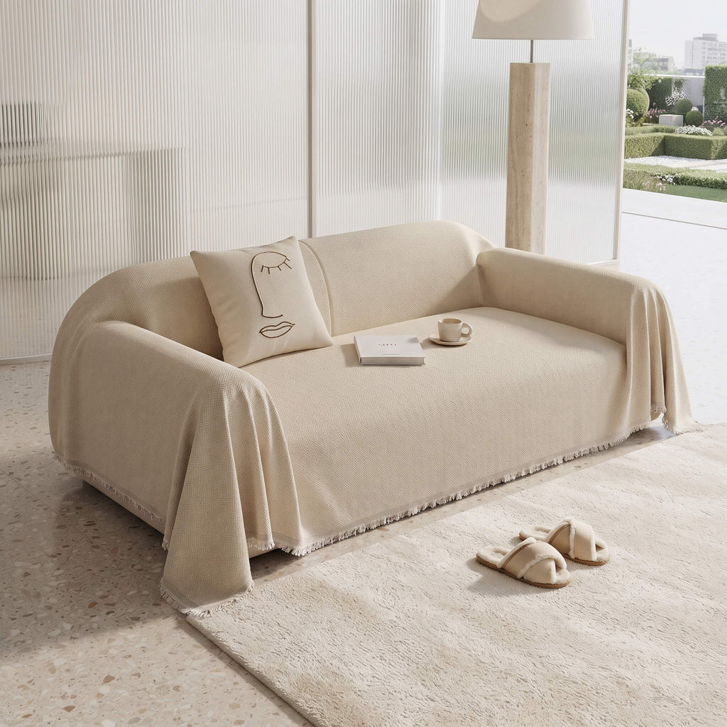 Beige sofa cover throw with the fringed edge pooling onto a rug