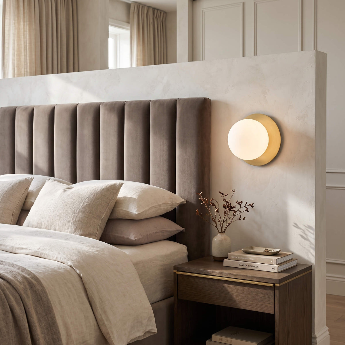 Globe wall sconce as bedside lighting beside an upholstered bed
