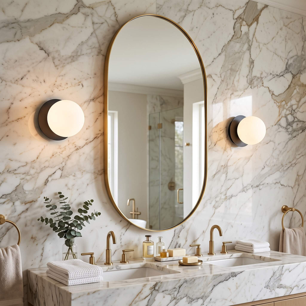 Pair of opal glass globe wall sconces flanking an oval bathroom mirror