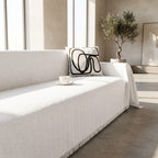 Close view of the white textured weave and fringed edge of the sofa cover throw