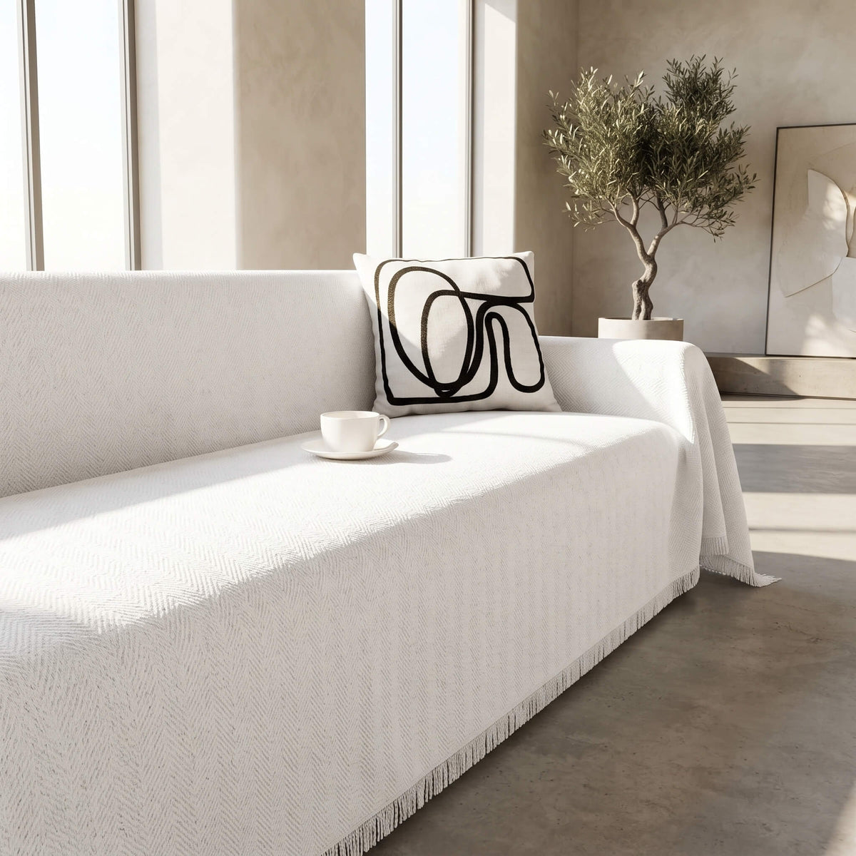 Close view of the white textured weave and fringed edge of the sofa cover throw