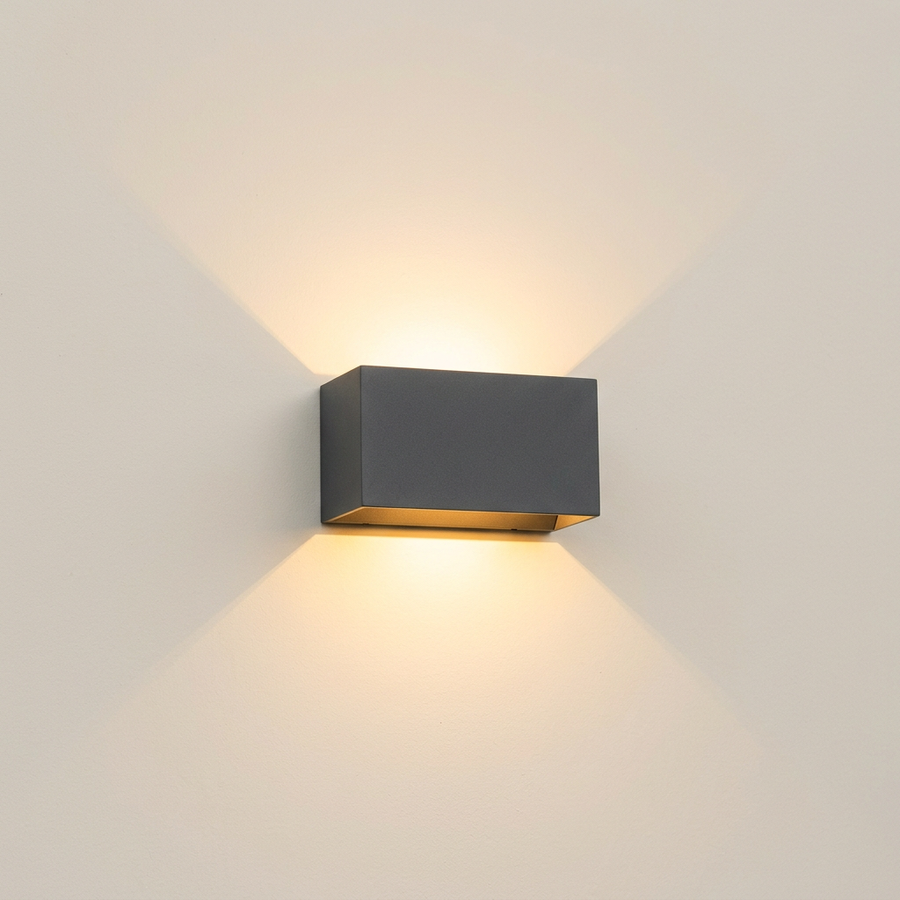 Matte black up and down wall light on a plain cream wall showing its twin beam pattern