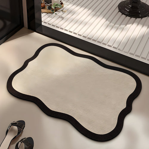 Ivory absorbent diatom mud bath mat, ivory centre with a dark wavy edge, on a bathroom floor