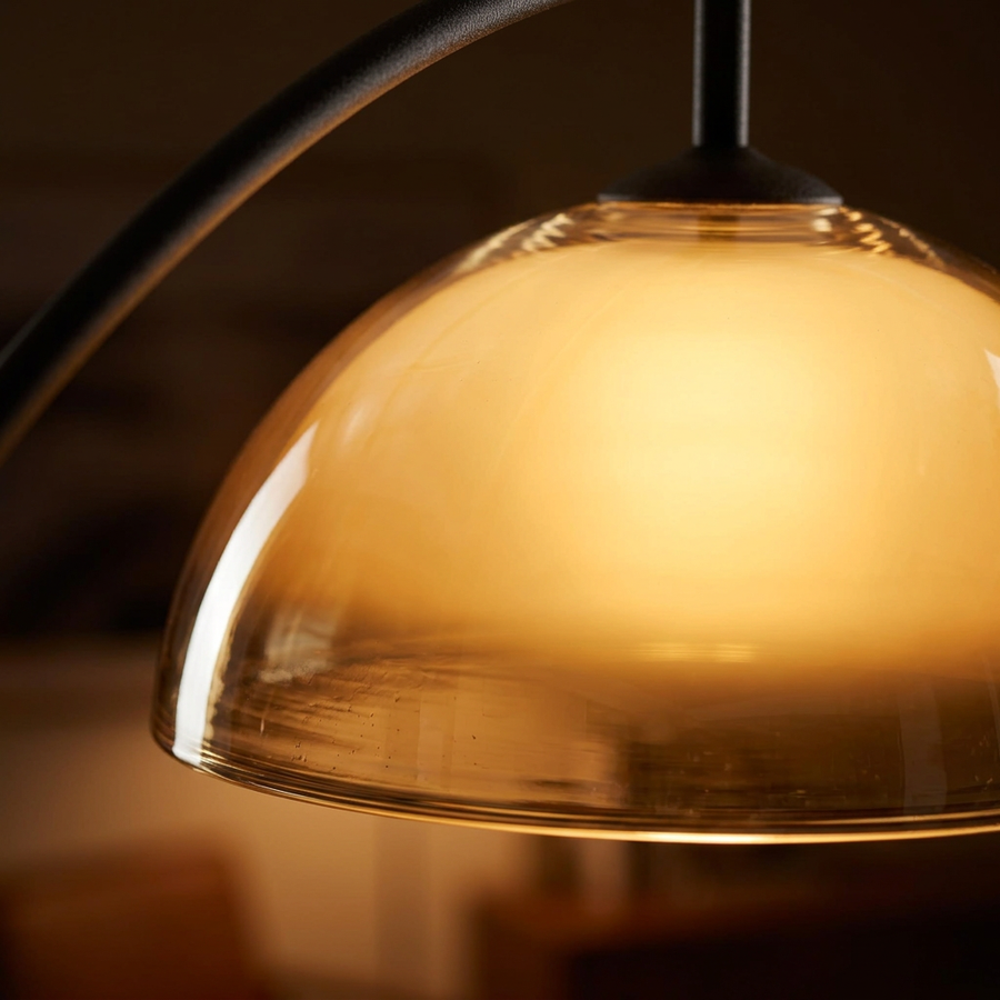 Close-up of the glowing amber glass dome shade on the Mid Century Arc Floor Lamp