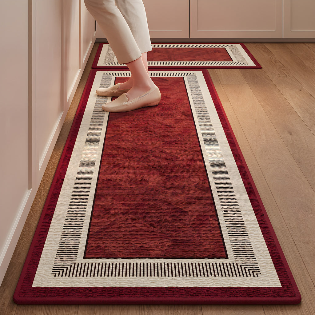 Ruby Key absorbent kitchen mat, deep red centre with a patterned cream border, on a timber floor