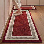 Ruby Key absorbent kitchen mat, deep red centre with a patterned cream border, on a timber floor
