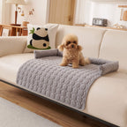 Grey quilted pet sofa mat on a cream sofa with a small dog