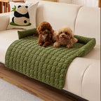 Olive green quilted pet sofa mat on a cream sofa with a small dog
