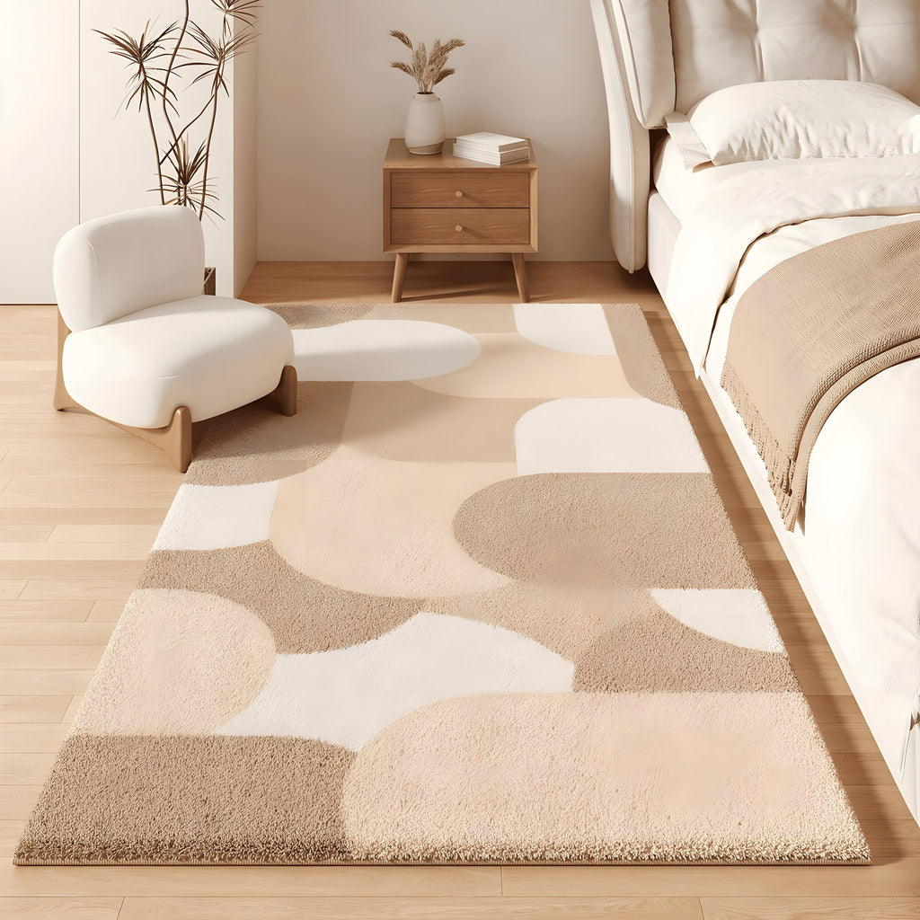Pebble faux cashmere bedroom rug, scattered pebble shapes in sand tones, beside a bed