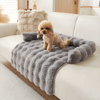 Charcoal plush faux fur pet sofa mat on a cream sofa with a small dog sitting on it