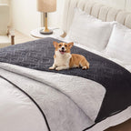 Black quilted waterproof bed cover on a bed with a corgi and the grey reverse folded back