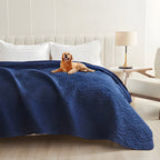 Dark blue quilted waterproof bed cover on a bed with a golden retriever lying on top