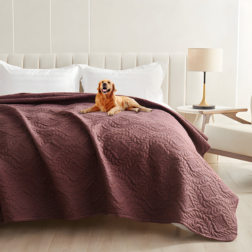 Plum quilted waterproof bed cover on a bed with a golden retriever lying on top
