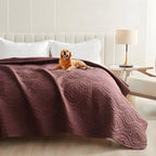 Plum quilted waterproof bed cover on a bed with a golden retriever lying on top