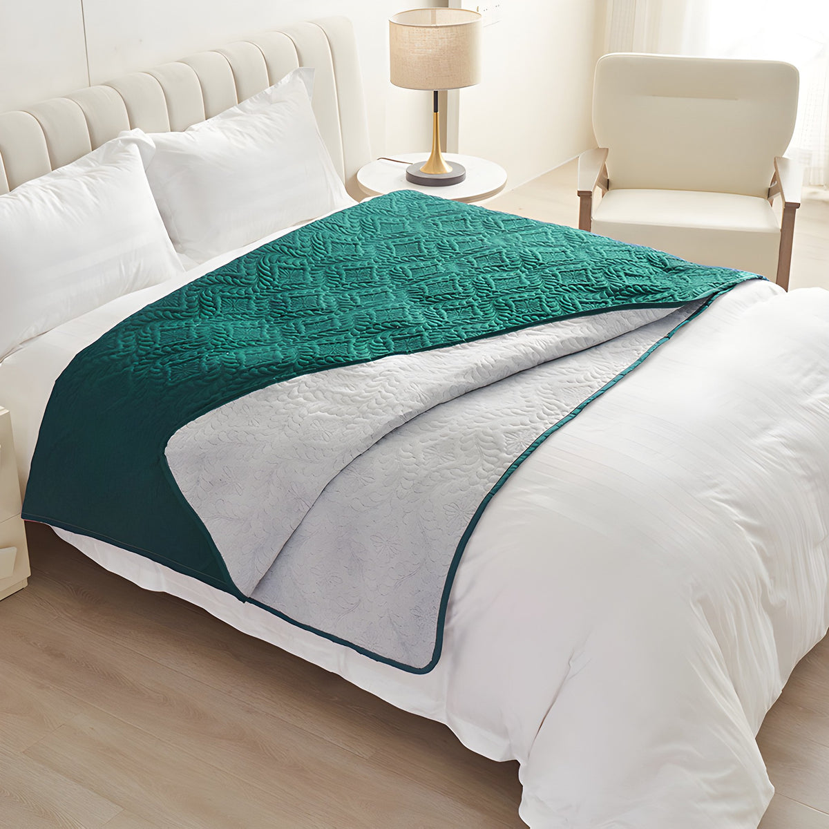 Emerald green quilted waterproof bed cover draped over a white made bed with the light reverse turned back