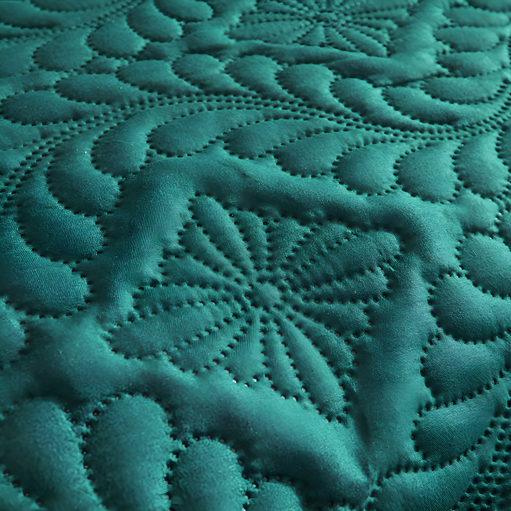 Flower medallion quilting on the emerald green bed cover laid flat