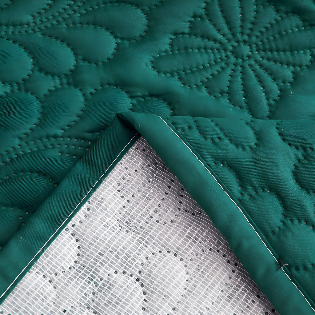 Folded corner of the quilted bed cover showing the bound edge and waterproof backing