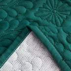 Folded corner of the quilted bed cover showing the bound edge and waterproof backing